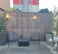 Terrace in Ružinov with wooden flooring, chairs, lights, and decorative lanterns.