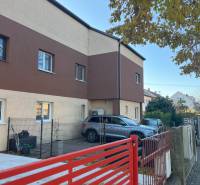 Two-story apartment building in Bratislava - Ružinov, with a parking lot and a red fence.