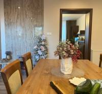Dining table with flowers, decorated tree, and kitchen in a 2-room apartment.