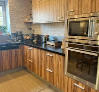 A kitchen with wooden cabinets, a built-in oven, and a window in a 2-room apartment.