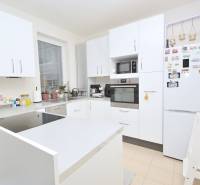 A bright kitchen in a three-room apartment, with white cabinets and appliances.