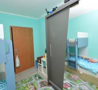 A children's room in a three-room apartment with a bunk bed and a colorful carpet on the floor.