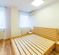 A bedroom with a wooden bed and a floor with a wooden decor in a 3-room apartment.