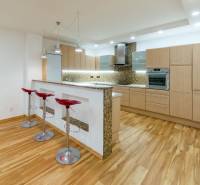 A kitchen in a three-room apartment with a wood-patterned floor and a bar counter.
