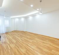 A spacious living room with wood-patterned flooring and built-in lighting in a three-room apartment.
