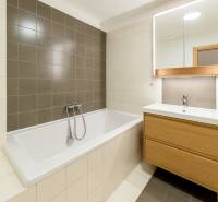Bathroom in a 3-room apartment with a bathtub, sink, and wooden cabinet.