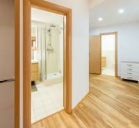 A hallway in a 3-room apartment with a wooden decor floor, bathroom, and cabinets.
