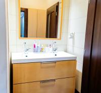 A bathroom with two sinks and a wooden cabinet in a three-room apartment.