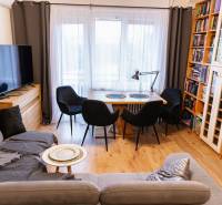Living room with a sofa, dining table, television, and bookshelf. Floor with wood decor.
