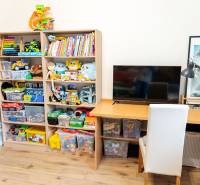 A children's room with shelves full of toys and a table in a 3-room apartment.