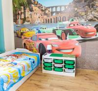 Children's room with a car theme, crib, and wooden decor flooring in a 3-room apartment.