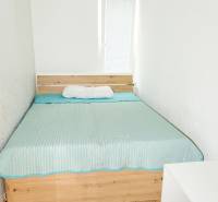 A bed with a blue blanket on a wooden floor, 3-room apartment.