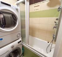 A bathroom in a 3-room apartment with a bathtub, washing machine, and dryer, tiles in earthy colors.