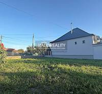 Plots in Kameničná with grassy area and a white house, ideal for living.