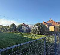 A plot for living in Kameničná with flat terrain and a house in the background.