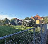 A residential plot in Kameničná with fencing, a house, and a garden by the road.