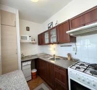 A kitchen in a 2-room apartment with a kitchen unit, a range hood, and a gas stove.