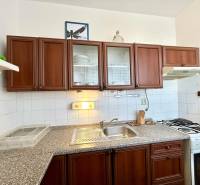 A kitchen unit in a 2-room apartment with dark wooden cabinets and white tiles.