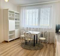 Dining room in a 2-room apartment with wood-patterned flooring and white furniture.