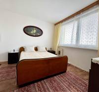 Bedroom in a 2-room apartment with a bed, name on the wall, large window, and carpets.