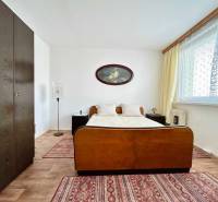 Bedroom in a 2-room apartment with a double bed, wardrobe, and floor with a wooden decor.