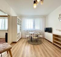 Living room in a two-room apartment with a wooden decor floor and light furniture.