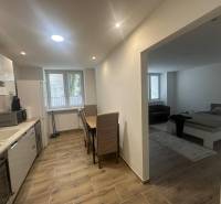A kitchen in a studio apartment with appliances and a wood-patterned floor.