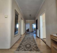 A hallway in a family house with a wooden decor floor and a carpet.