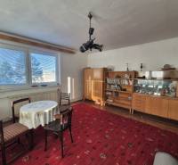 Living room with furniture and a table on a red carpet in a family house.