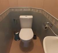 Bathroom with toilet in a 4-room apartment; light tiles, sink, and mirror.