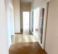 A hallway with light walls and a floor with a wood decor in a 4-room apartment.
