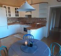 A kitchen in a 4-room apartment with a wood-patterned floor, a dining table, and a white kitchen unit.