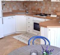 A kitchen with white cabinets, a wooden decor floor, and a table in a 4-room apartment.