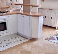 A kitchen in a 4-room apartment with a wooden decor floor and white cabinets.