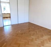 A room with a wooden decor floor and a sliding wardrobe in a 4-room apartment.