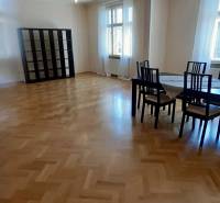 Spacious living room with a table and chairs, wood-decorated flooring, 4-room apartment.
