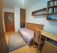 A room in a family house with a desk, a sofa set, and shelves.