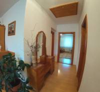 A hallway in a family house with a wooden decor floor, wooden furniture, and a plant.