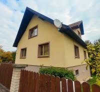 A family house in Medzev with a wooden fence and a garden, in an autumn setting.