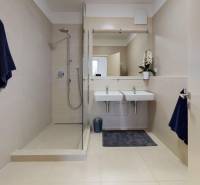 A bathroom in a 2-room apartment with two sinks and a shower; subtle beige tiles.