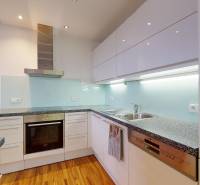 A kitchen in a 2-room apartment with white cabinets and a wood-patterned floor.