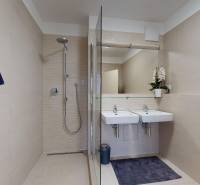A spacious bathroom with two sinks and a shower in a 2-room apartment.