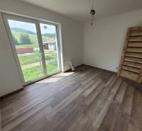 A room in a family house with a wooden decor floor and large windows.