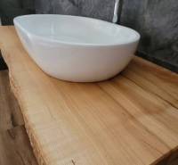 A bathroom in a family house with a sink on a wooden countertop and dark tiles.