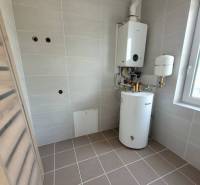 Technical room with a boiler and a gas boiler in a family house. The walls are tiled.