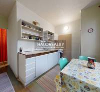 A kitchen in a 3-room apartment with light furniture and a table with a patterned tablecloth.
