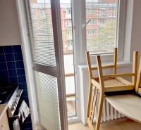 Kitchen in a studio apartment with wood-patterned flooring and balcony doors.