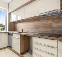 A kitchen in a 3-room apartment with light cabinets and wooden elements, with a large window.