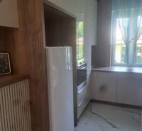 A kitchen in a 3-room apartment with tiles, a white appliance, and a large window.