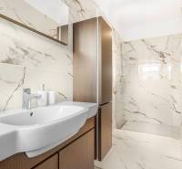 Bathroom with a shower and a sink in a 3-room apartment, light tiles with a marble pattern.